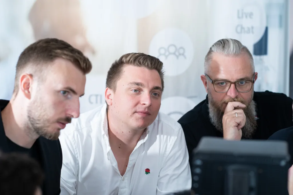 Drei Kollegen arbeiten konzentriert gemeinsam an einer Aufgabe, während sie auf einen Bildschirm schauen.