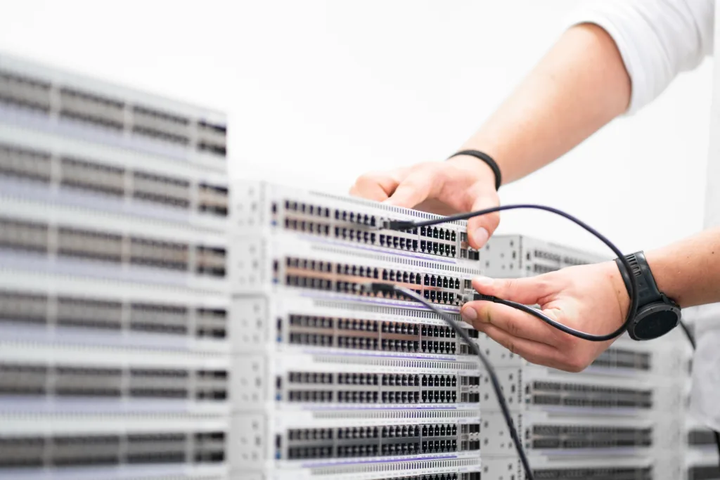 Hände verbinden Netzwerkkabel mit Serverhardware in einem Rechenzentrum.