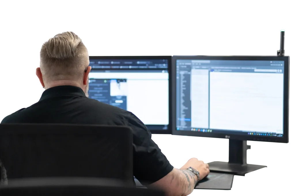 Ein Mitarbeiter arbeitet mit zwei Bildschirmen im Büro und konzentriert sich auf seine Aufgaben.