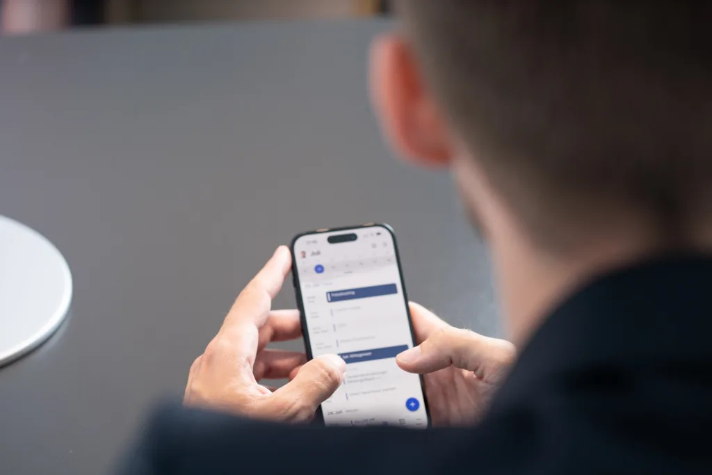 Eine Person überprüft ihren Kalender und plant Termine auf einem Smartphone.