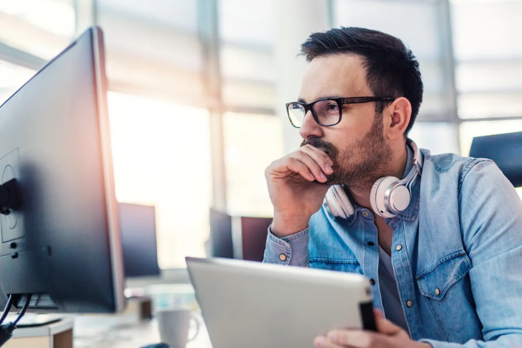 Pensive young modern developer working alone at the office