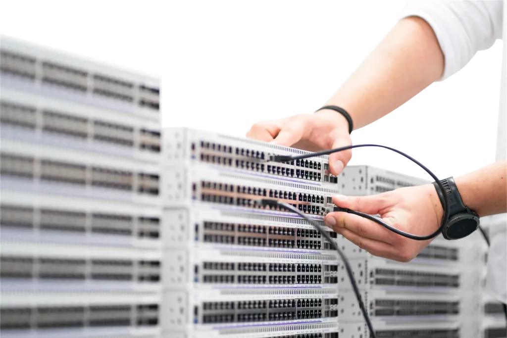 Hände verbinden Netzwerkkabel mit Serverhardware in einem Rechenzentrum.