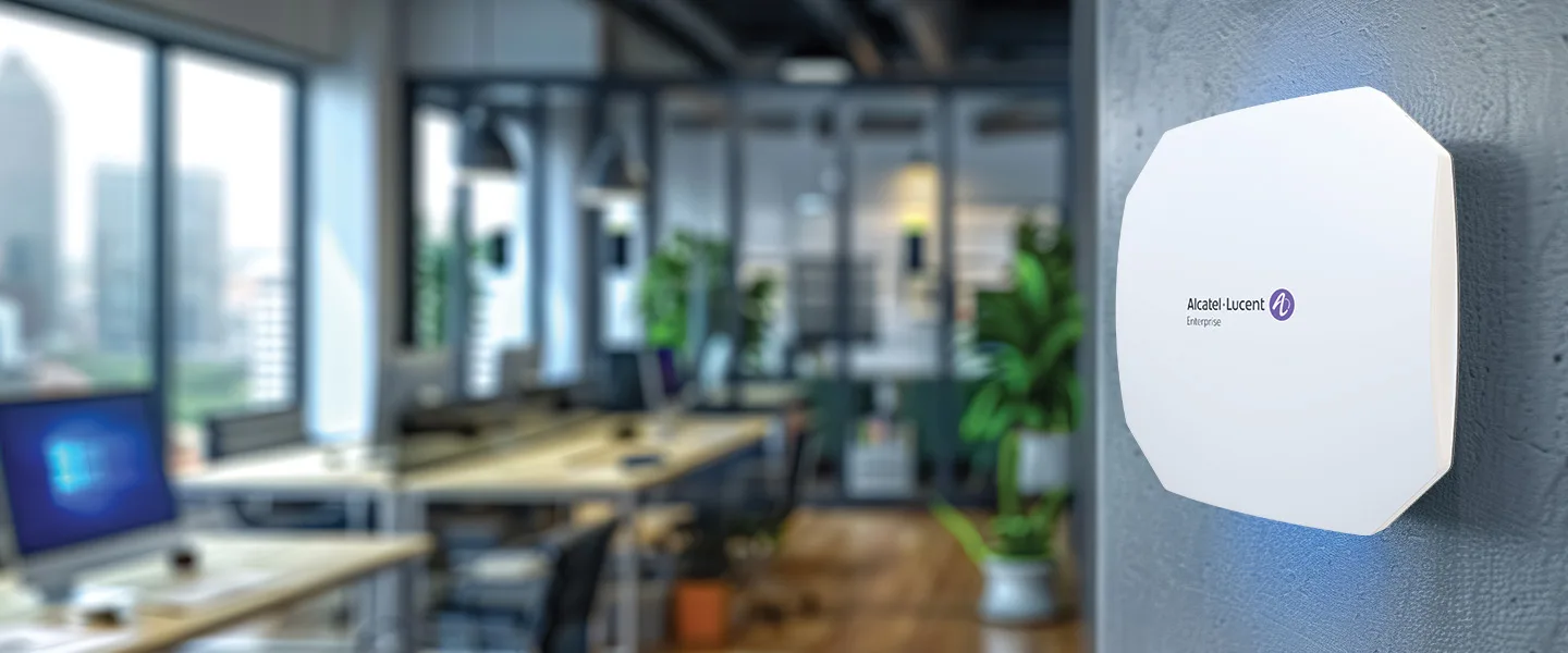 im Hintergrund ein modernes Büro, im Vordergrund hängt ein AccessPoint der Marke Alcatel-Lucent an der Wand