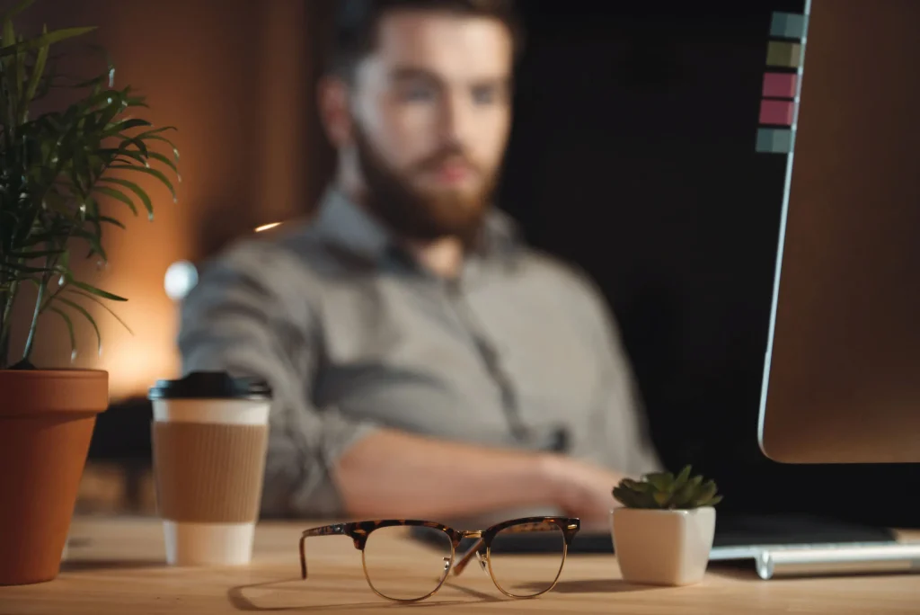 Junger Mann sitzt mit einem Kaffe vor dem PC und nimmt an einem Webinar Teil